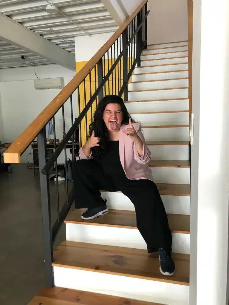Integrante del equipo de KIKU posando con gesto divertido en las escaleras de la oficina