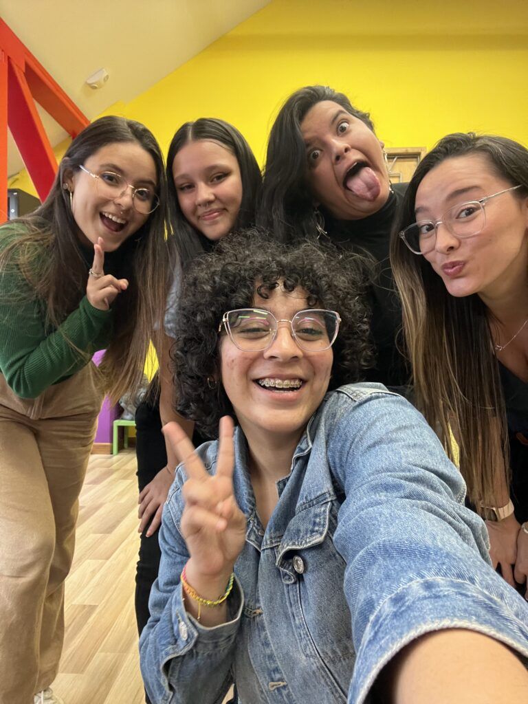 Cinco integrantes del equipo de KIKU sonriendo en un selfie frente a una pared amarilla