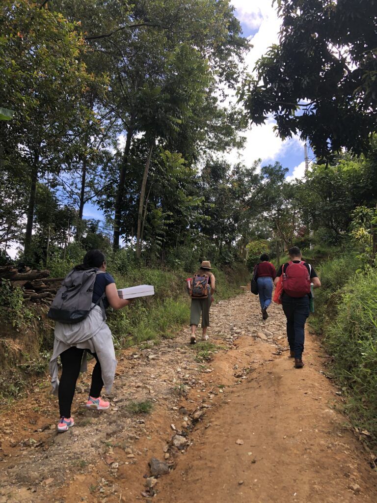 Equipo de KIKU caminando por un sendero de tierra rodeado de árboles durante una actividad al aire libre